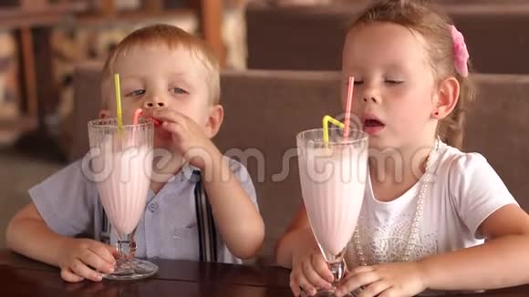 两个孩子在户外咖啡馆喝奶昔视频的预览图