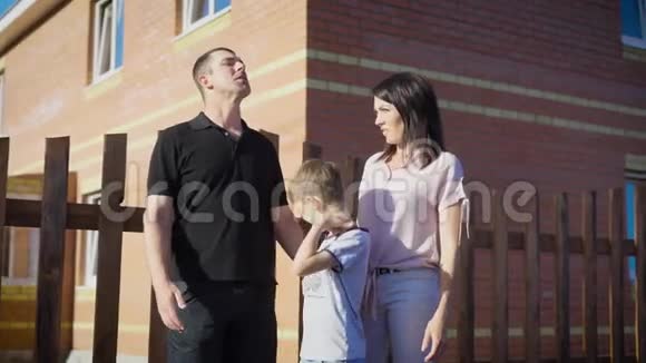 一家人站在房子外面骄傲的父母和年幼的儿子视频的预览图