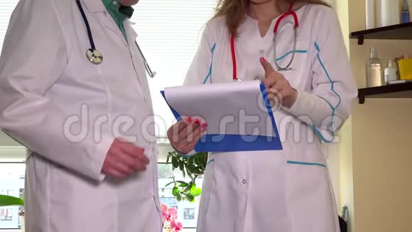 身穿白大褂的医生在医院的柜子里讨论病人的文件视频的预览图