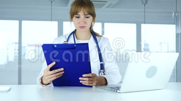 年轻女医生阅读病人的医疗报告诊断视频的预览图