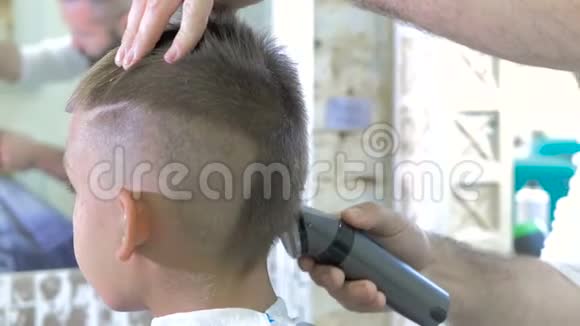 理发师在美容院给带理发器的小男孩理发视频的预览图