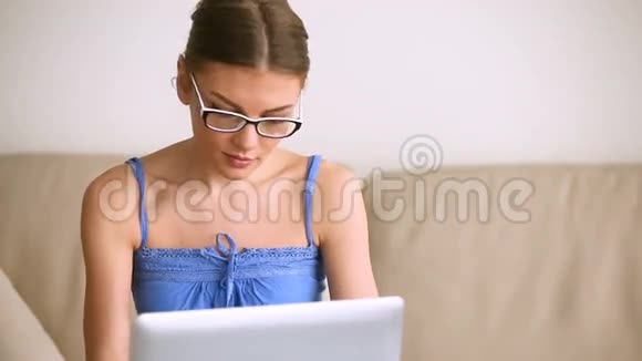 年轻漂亮的女孩戴着笔记本电脑的眼镜微笑着拍照视频的预览图