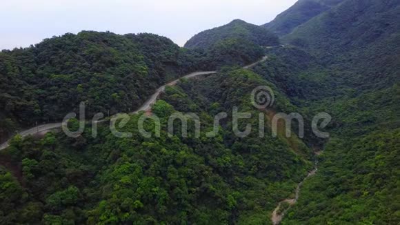 台湾绿树林中的汽车沿着弯曲的蛇形道路行驶鸟瞰图视频的预览图