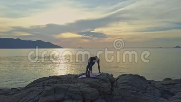 在海面上日出时观影女孩手持瑜伽姿势视频的预览图