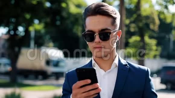 有魅力的年轻商人在外面用无线耳机打电话快乐的人说话视频的预览图