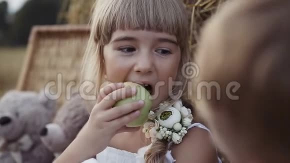 小女孩吃一个绿色的苹果酷酷的小男孩和小女孩坐在干草堆下面视频的预览图