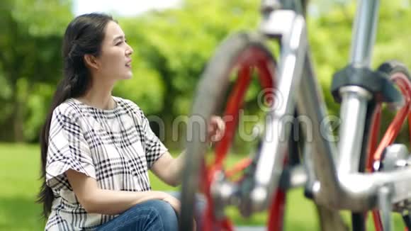 亚洲妇女在户外骑自行车后坐着休息视频的预览图