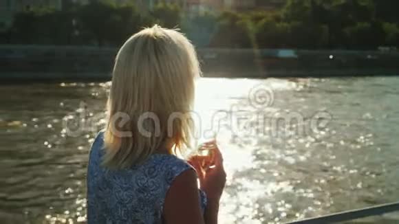 河流巡航一个拿着一杯酒的女人正在船上旅行从后面看到一个闪亮的背景视频的预览图