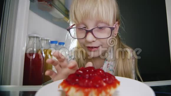 一个小女孩偷偷地在冰箱里尝了一个草莓蛋糕童年的恶作剧快乐的童年视频的预览图