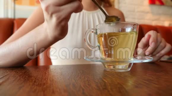 那个女孩用绿茶在透明的杯子里搅拌糖4K慢动作视频的预览图