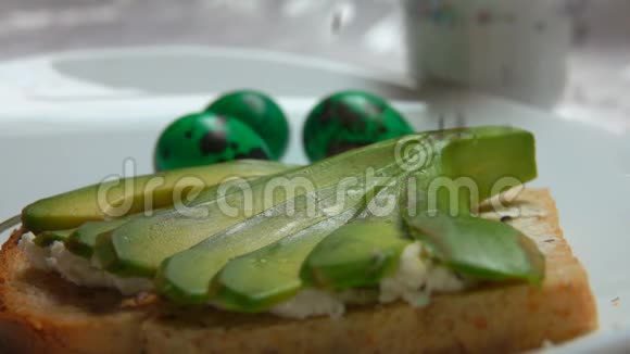 在复活节彩蛋背景上撒上黑芝麻的鳄梨三明治视频的预览图