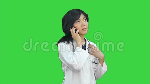 亚洲女医生在绿色屏幕上使用智能手机Chroma键视频的预览图