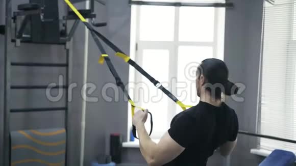 一名男子用体操戒指做俯卧撑的后视图视频的预览图