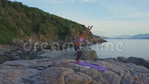 Flycam围绕着女孩在海岸的山丘上摆姿势旋转视频的预览图