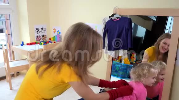 保姆女人在镜子旁和蹒跚学步的女孩玩耍视频的预览图