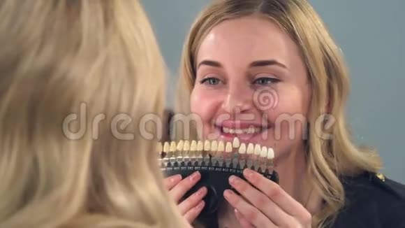 一个金发女孩看着镜子前面的结果牙齿美白在一个特殊的颜色尺度女孩很高兴视频的预览图