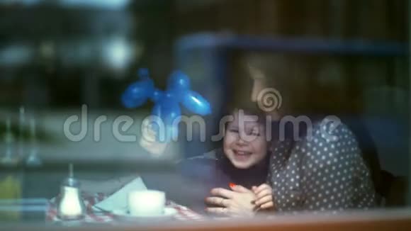 母亲和她的小儿子抱着巴伦在咖啡馆里笑视频的预览图