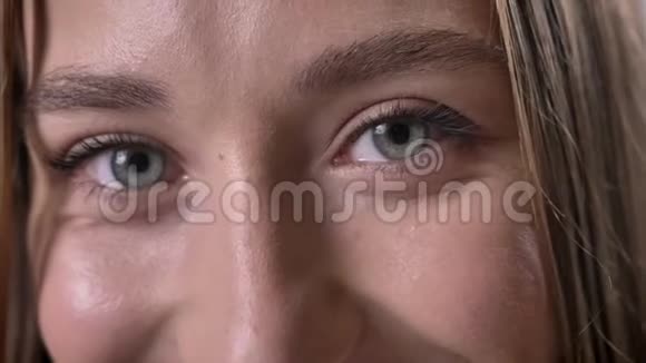 年轻的森森女孩的眼睛在镜头前看着微笑着灰色的背景视频的预览图