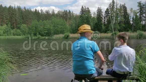 父子俩在河边的长凳上钓鱼视频的预览图