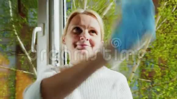 我们心情愉快地打扫房子年轻的女人擦着房子里的窗户微笑着正面观点视频的预览图