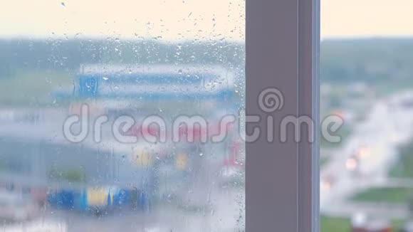 雨滴沿着窗户的特写从潮湿的窗户看多栋楼的房子模糊视频的预览图