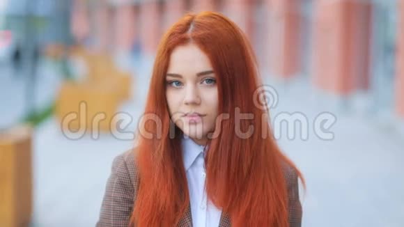 美丽迷人的年轻红发女孩穿着棕色的商务夹克在城市的街道上看着镜头斯蒂迪达姆视频的预览图
