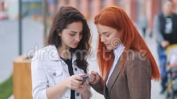 年轻漂亮的女商人们穿着对智能手机感兴趣的衣服风摇曳着头发积极的时刻视频的预览图
