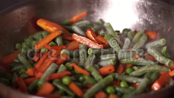 水流在装有蔬菜的热锅里橙色胡萝卜与冷冻豌豆和硅果酱亲密视频的预览图