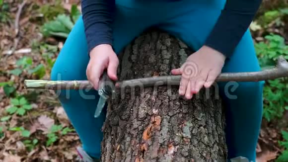 小女孩或男孩用瑞士刀在森林里锯一块木头没有人视频的预览图