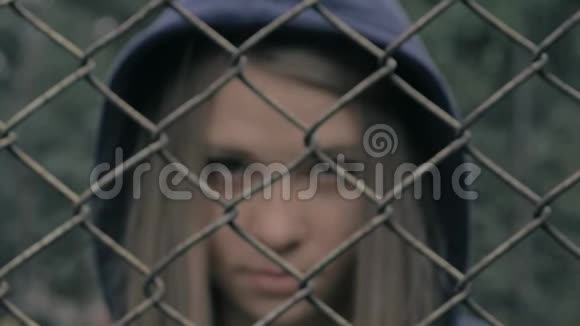 铁栅栏后忧郁而悲伤的金发白种人女孩的肖像年轻女子被关在铁栅栏监狱里视频的预览图