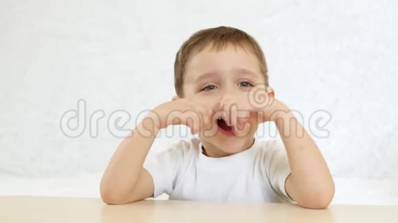 一个孩子很高兴在一个华夫饼锥里吃一个巧克力冰淇淋坐在桌子上背景是白色的视频的预览图