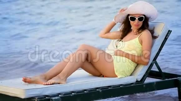 美丽的年轻女子戴着眼镜在海边晒太阳视频的预览图