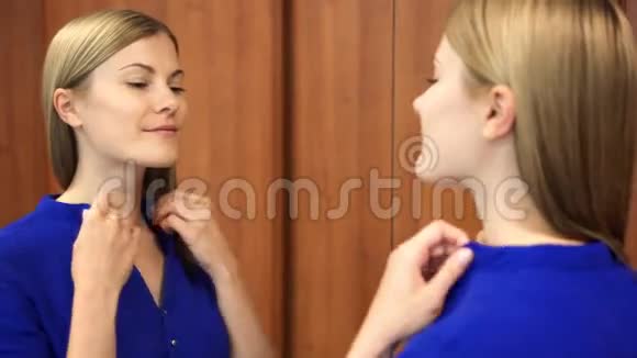 穿着深蓝色上衣的漂亮女人准备约会检查衣服和镜子里的脸视频的预览图