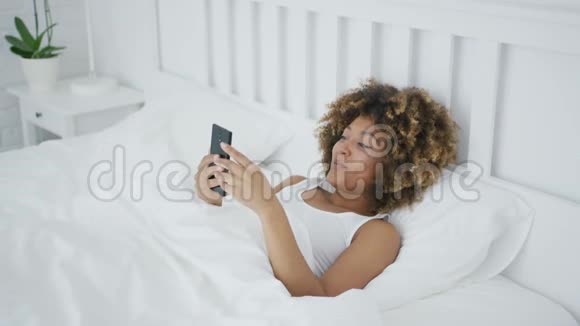 在床上微笑的女人在网上聊天视频的预览图