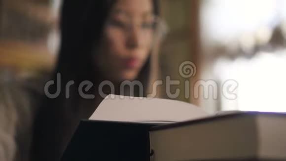 年轻的亚洲妇女坐在图书馆的桌子旁看书的肖像视频的预览图