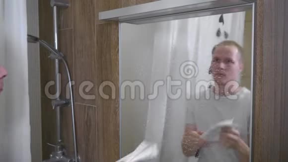 一个人打扫浴室里的镜子一个年轻人用纸巾清洁浴室镜子4K视频的预览图