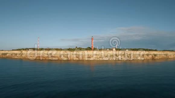 从海洋和陆地上的旧灯塔和风力发电机上俯瞰海岸线视频的预览图