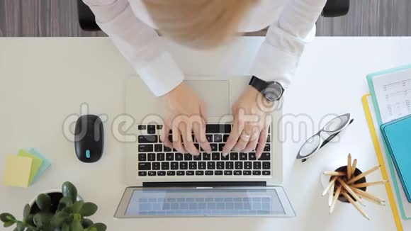 办公室里一个女人在笔记本电脑上快速打字的俯视图视频的预览图