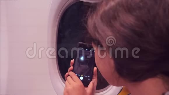 航空飞机概念年轻女孩正坐飞机在下面的智能手机夜城拍照视频的预览图