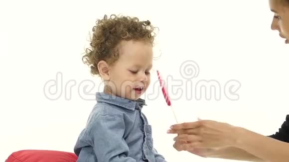 小男孩妈妈给了他一个美味的棒棒糖白色背景慢动作视频的预览图
