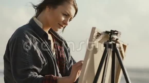 美丽的女人在海边画这幅画视频的预览图