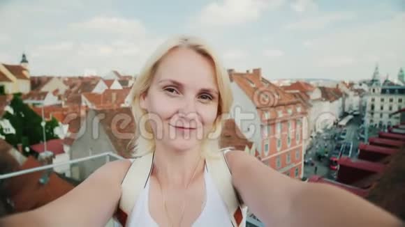 一位年轻女子在视频中拍摄了奥地利老欧洲城市格拉茨的背景在看着视频的预览图