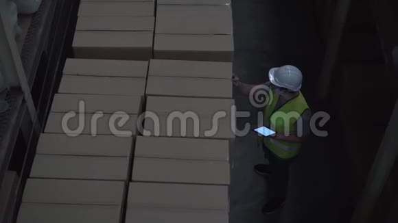 仓库工作人员戴着安全安全帽正在库存室用数码平板电脑检查订单细节视频的预览图