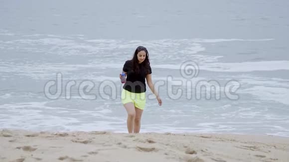 美丽的女孩走在海边的沙滩上视频的预览图