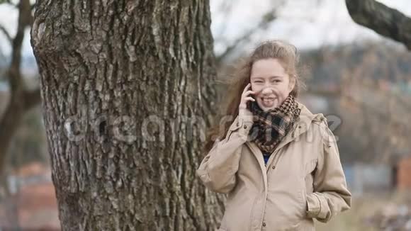 穿着复古复古的浅棕色米色外套的年轻孕妇带着手机打电话视频的预览图