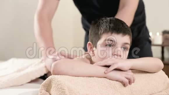 男性理疗师按摩师为躺在按摩床上的小男孩做一个疗愈放松的按摩肩膀和视频的预览图