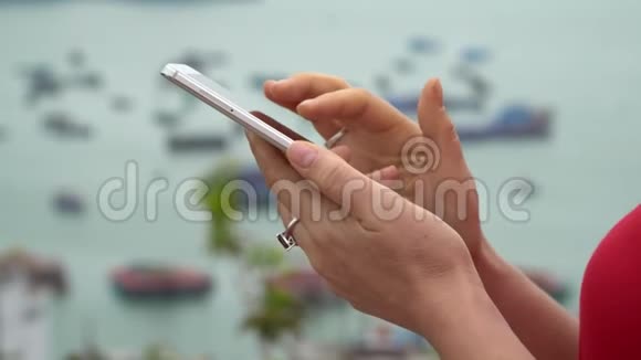这位女士在智能手机上看信息女人用智能手机在海湾的背景下视频的预览图