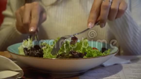 女人在一家室内咖啡馆里吃沙拉靠近盘子视频的预览图