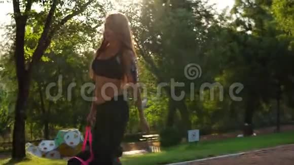 美丽的黑发女子短运动上衣和袖标步行与运动袋在公园健康运动女性视频的预览图