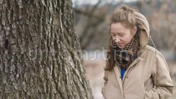 年轻漂亮可爱的女人穿着米色紧身衣和格子围巾走着眨着眼睛看着镜头稳定的凸轮视频的预览图